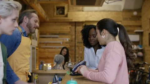 Waiter serving coffee and accepting payment from customers at bike garage cafe Video stock 108034575