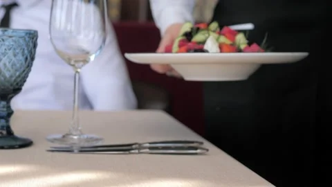 A waiter serving a customer in a restaurant. Close-up of a waiter putting plates Video stock 156438946