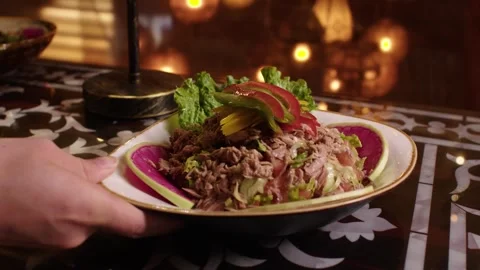 Waiter serving a delicious shredded beef salad on a decorated table in a luxury Stock Footage 345133858