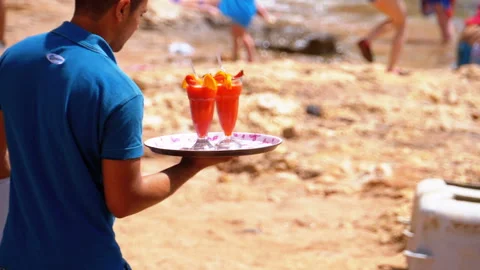 Waiter Serving Drinks on the Beach, Egypt. Waiter holding a tray with tropical Stock Footage 112184525