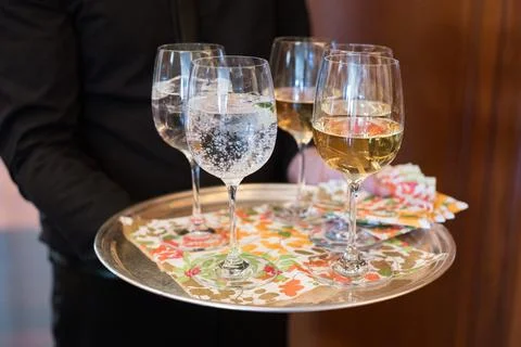 Waiter serving a selection of drinks on a decorative tray during a social Stock Photos