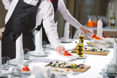 Waiter serving table in the restaurant preparing to receive guests. Stock Photos