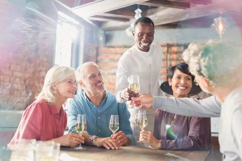Waiter serving white wine to couples at restaurant table Stock Photos