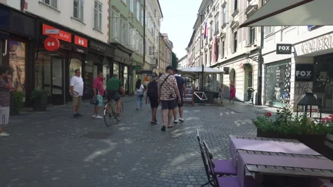 Waiter sets the table outdoor and people walk on the narrow street in Ljubljana Stock Footage 182010434