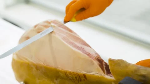 Waiter slicing jamon ham into thin pieces at buffet event Stock Footage 314458105