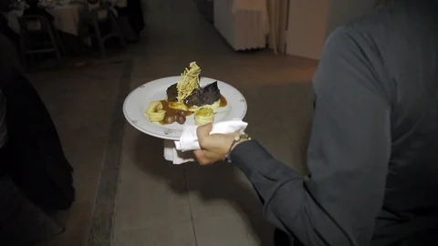 Waiter takes the meat to a table at a wedding Stock Footage 105828633