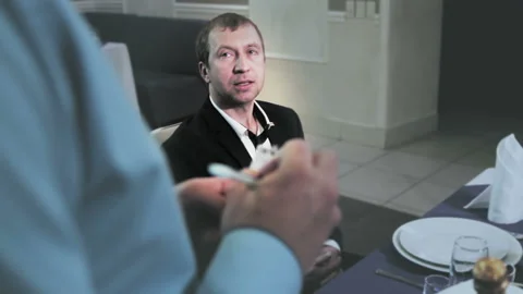 A waiter takes an order from a middle-aged couple in a restaurant and writes his Stock Footage 97577963