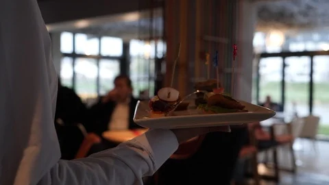 Waiter with a tray of food in the restaurant, walking to customer.  Stock Footage