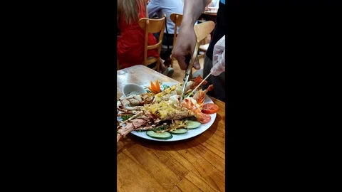 A waiter uses scissors to cut a lobster for customers at a restaurant Stock Footage 304221917