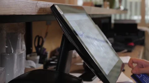 A waiter working at a computer in a cafe, he swipes a card through the terminal. Video stock 262051331