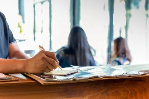 Waiter writing down customer order at the counter bar in cafe. Stock Photos