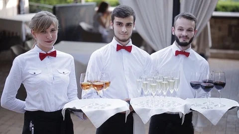 The waiters greet guests with alcoholic drinks. Champagne, red wine, white wine Stock Footage