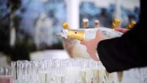 The waiter's hand pours champagne into glasses in the catering event party Stock Footage