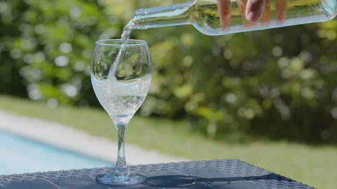 Waiter's hand pours chilled white wine from a glass bottle into elegant glass. Stock Footage 345505102