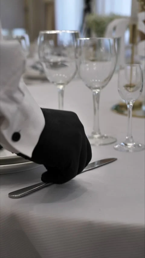 Waiter's hands laying out cutlery on a dining table. Table setting Stock Footage 306411220