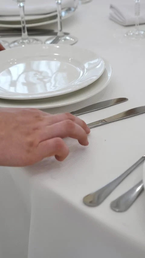 Waiter's hands laying out cutlery on a dining table. Table setting Stock Footage 313963138