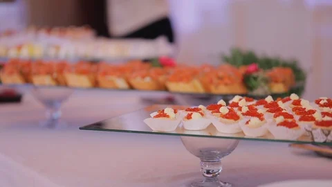 Waiters put luxury snacks with red caviar from tray on table Stock Footage 122037368
