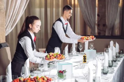 Waiters serving table in the restaurant preparing to receive guests Stock Photos