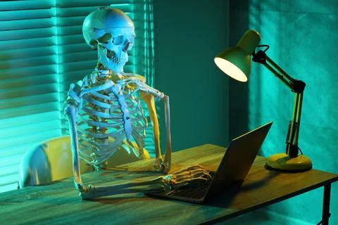 Waiting concept. Human skeleton sitting at wooden table with laptop indoors Stock Photos