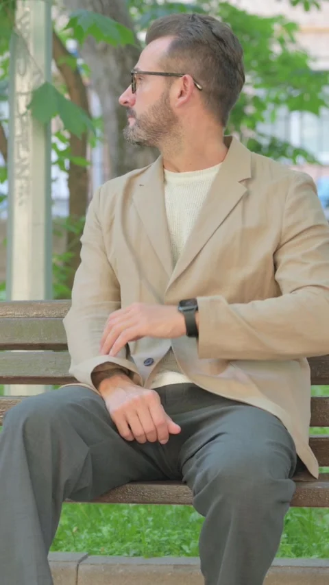 Waiting Young Man Checking Time while Sitting Outdoor, Vertical Video Stock Footage 319017840