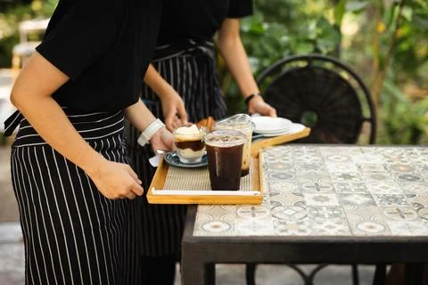Waitress with apron serving iced coffee to customer at cafe. Stock-Fotos