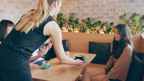 Waitress brings three millennial friends coffee in cafe on wood bench in Austral Video stock 199459264