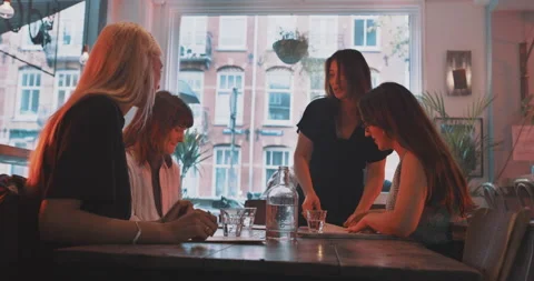 Waitress brining menu to the table  of friends Stock Footage 203582689