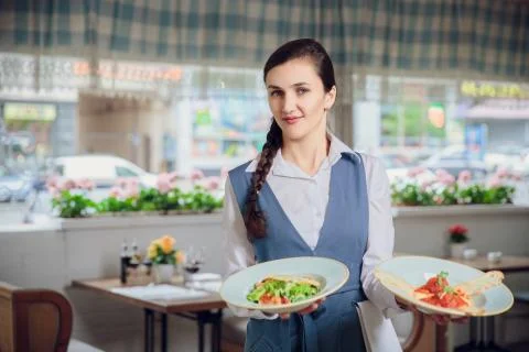 Waitress is carrying two plates with restautant delicious dishes Stock Photos