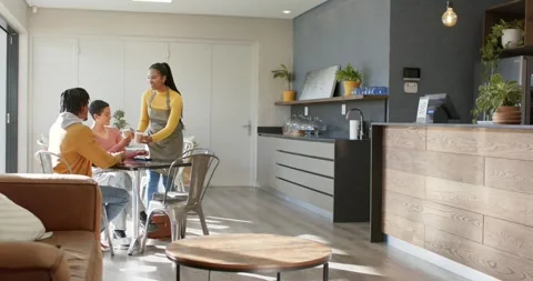 Waitress entering serving coffee mugs to diverse couple at cafe table, copy Stock Footage 339651465