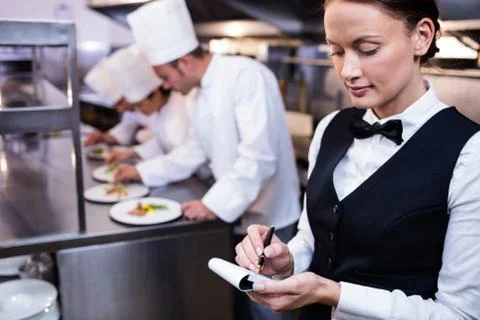 Waitress with note pad in commercial kitchen Photos