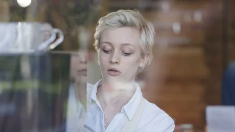 Waitress preparing coffee and customers making payment at cafe counter Stock Footage 108013476