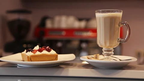 The waitress puts the cake next to the latte on the bar Stock Footage 96835919