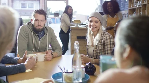 Waitress serving coffee to group of friends sitting together in cafe Stock Footage 108039888