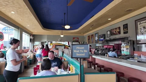Waitress serving customers in a retro diner with blue ceiling Stock Footage 336352125