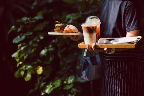 Waitress serving iced coffee and croissants in cafe outdoor. Stock Photos