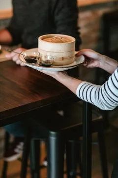 Waitress serving a man at a restaurant table with a plate featuring two sma.. Stock Photos