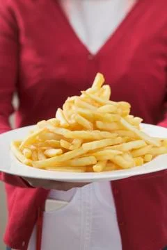 Waitress serving plate piled high with chips Stock Photos