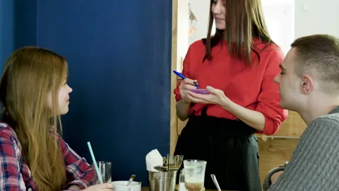 The waitress taking the order from a young couple in the restaurant. 4K Video stock 98933501