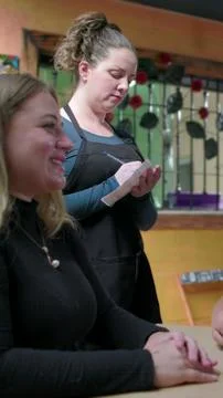 Waitress writing an order on a notepad while a smiling blonde customer sits at Foto stock