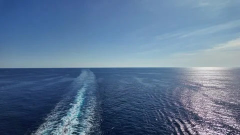 Wake of a Cruise Ship Cutting through the Calm Blue Ocean under a Bright Sky wit Stock Footage 283548034