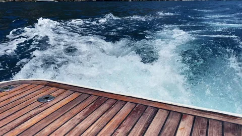 Wake foam from riding speed boat along the water, wood stern of luxury yacht for Stock Footage 344796792