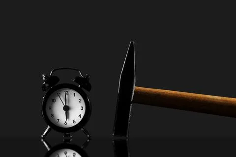 Wake up with a hammer on a black background. Black old style alarm clock is.. Stock Photos