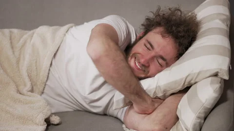 Wake up. Man throws pillow at a girlfriend. Sleep on the sofa the guy was guilty Stock Footage 159233053