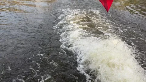 Wake, produced by a boat, vigorously churning dark water surface, generating Stock Footage 332834707