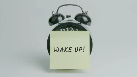 Wake Up Text or Word on Yellow Note Paper Sticking onto Black Alarm Clock Stock Footage 299463428