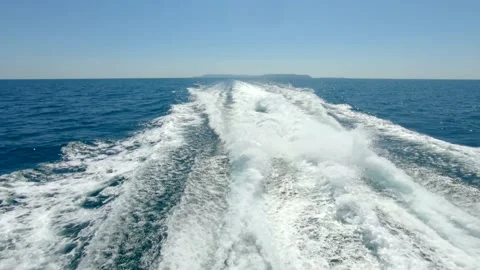 Wake waves from large speed boat ship traveling in open ocean leaving island Stock Footage 142529226