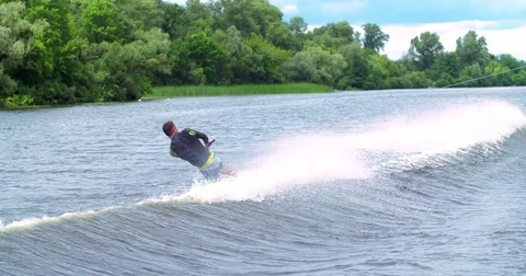 Wakeboarder doing tricks 4k wakeboarding video. Man rides behind boat jumps flip Stock Footage 79239507