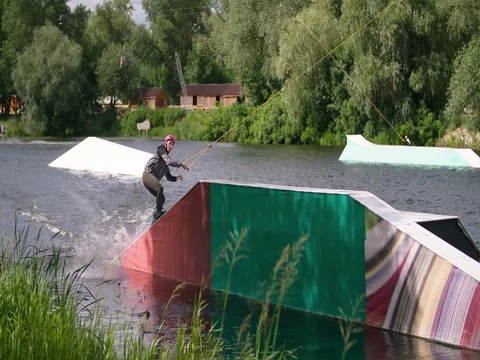 Wakeboarder doing tricks at cable wake park 4k wakeboarding video Stock Footage 79239223