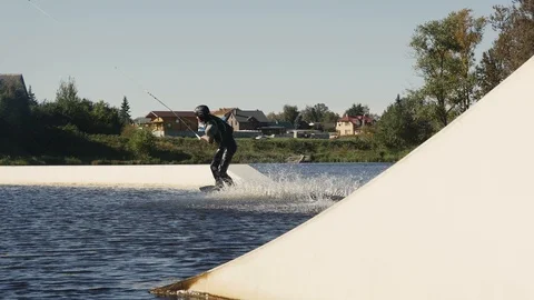 Wakeboarder guy riding on string making trick on lake Stock Footage 85999458