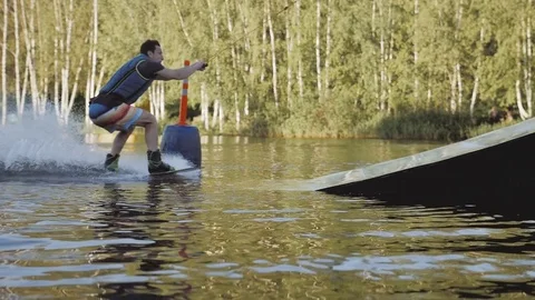 Wakeboarder making tricks on the sea or lake. Wakeboarding. Water sports on the Stock Footage